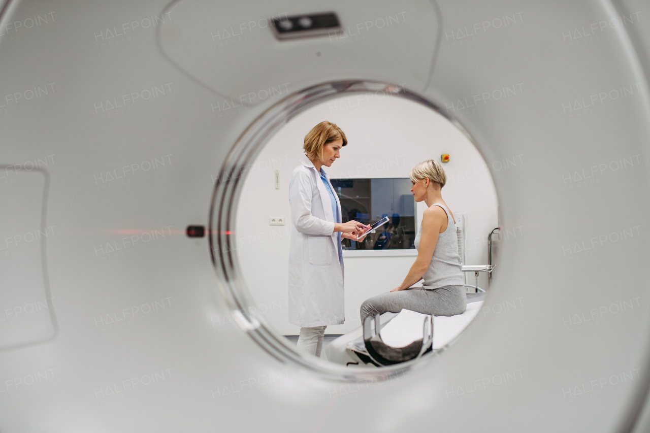 Doctor sharing positive CT scan results with smiling patient in imaging room, medical setting.