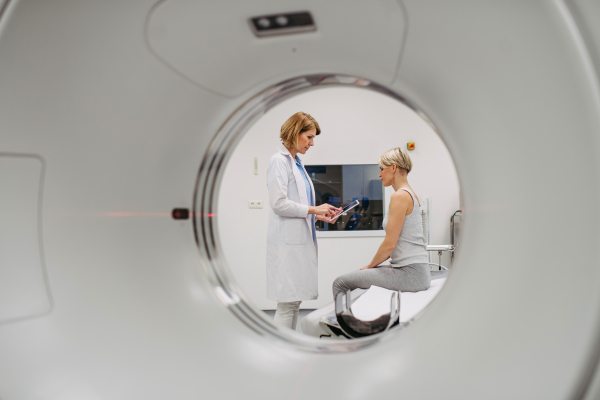 Doctor sharing positive CT scan results with smiling patient in imaging room, medical setting.