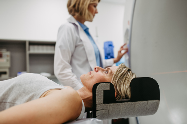 Patient positioned for head scan with laser alignment in CT scanner. Red laser lines.