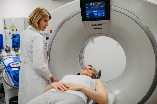 Female doctor operating CT machine and preparing patient for scan