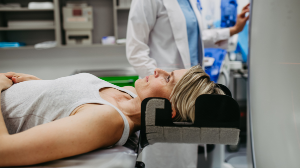 Patient positioned for head scan with laser alignment in CT scanner. Red laser lines.