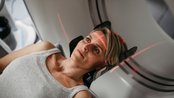 Patient positioned for head scan with laser alignment in CT scanner. Red laser lines.