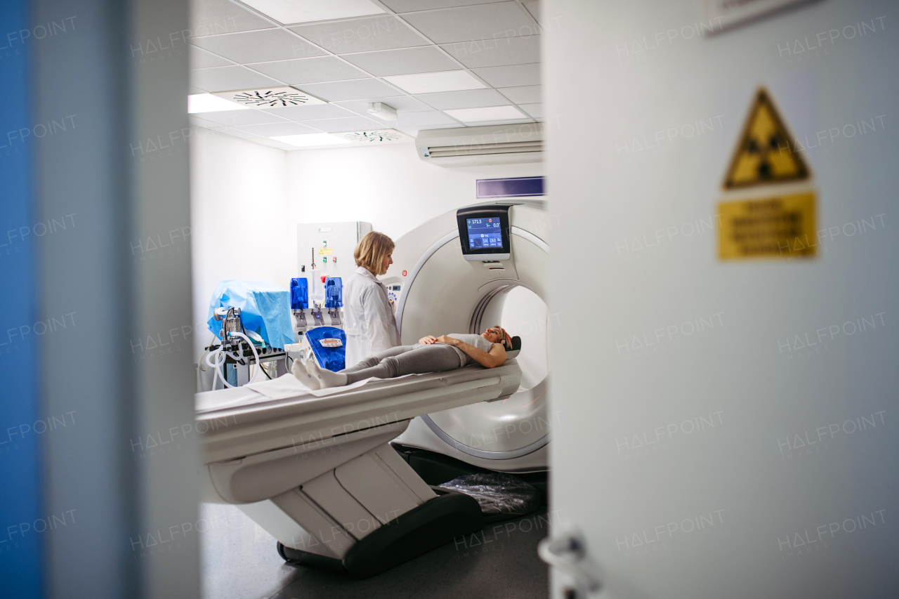 Female doctor operating CT machine and preparing patient for scan