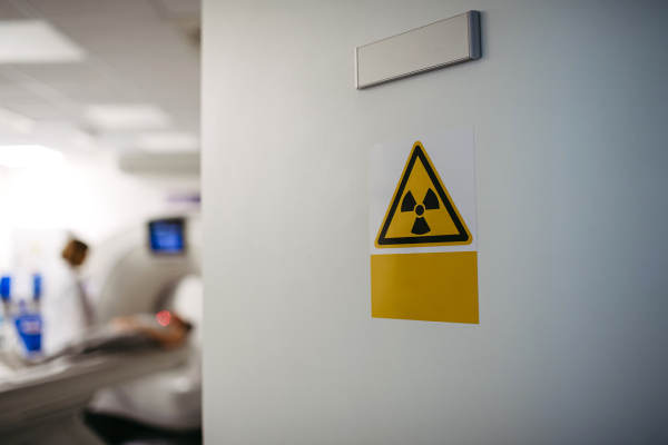 CT scan in progress behind radiation warning sign, safety protocol.