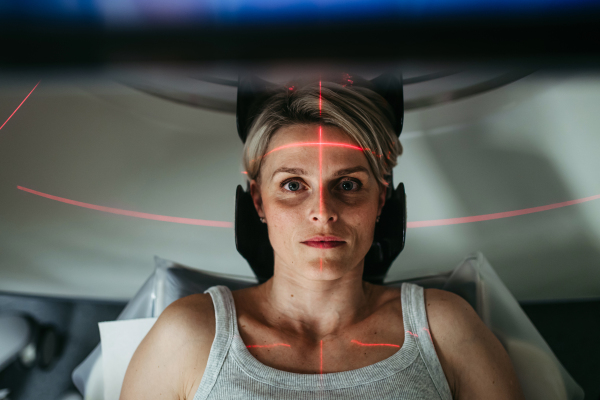 Patient positioned for head scan with laser alignment in CT scanner. Red laser lines.