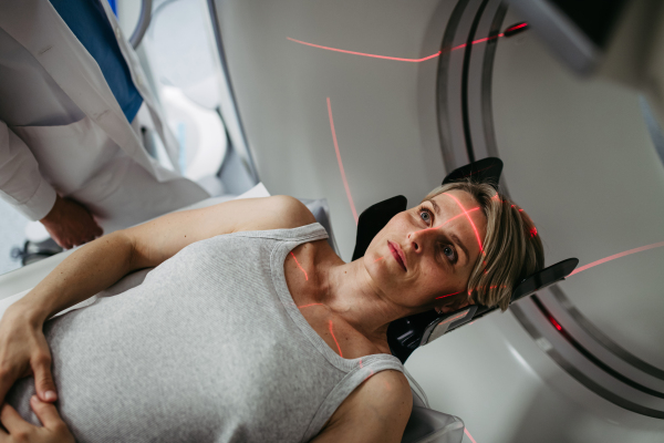 Patient positioned for head scan with laser alignment in CT scanner. Red laser lines.