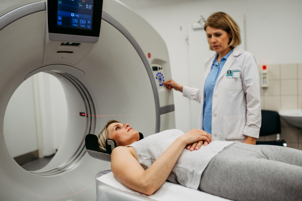 Female doctor operating CT machine and preparing patient for scan