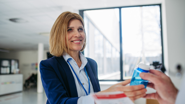 Female medical sales representative introducing pharmaceutical products to doctor. Hospital setting.