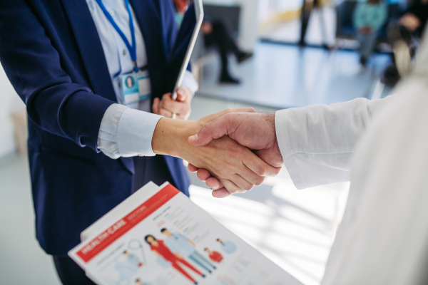 Business interaction, handskae between pharma rep and healthcare worker.