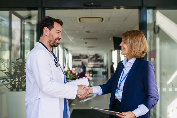 Confident female medical sales representative introducing herself to doctor. Hospital setting.