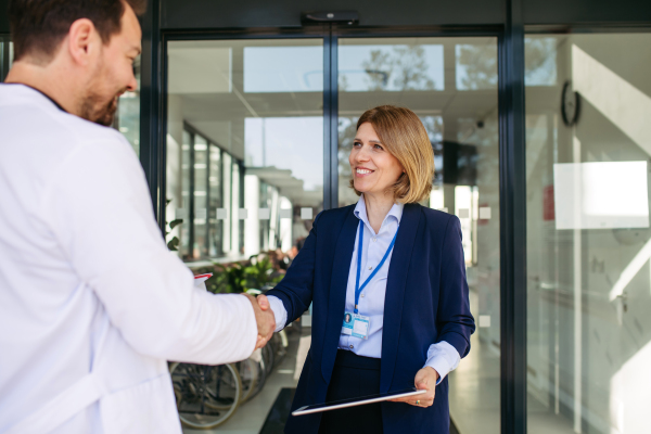 Confident female medical sales representative introducing herself to doctor. Hospital setting.