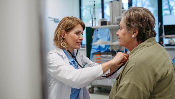 Geriatrician listening to senior patient's heartbeat. Routine health exam for elderly woman.