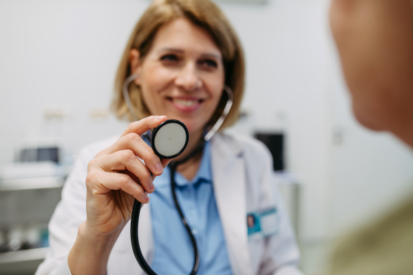 Geriatrician doctor examining elderly patient with stethoscope.. Routine health exam for elderly woman.