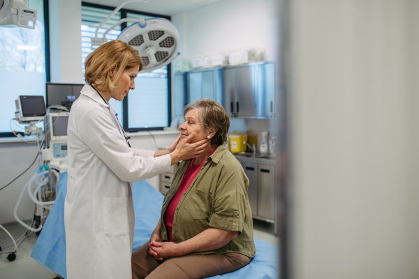 Doctor palpating lymph nodes during medical examination of senior female patient.