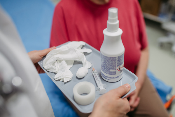 Close up of doctor carry a tray with vaccination tools. Elderly patient being vaccinated.