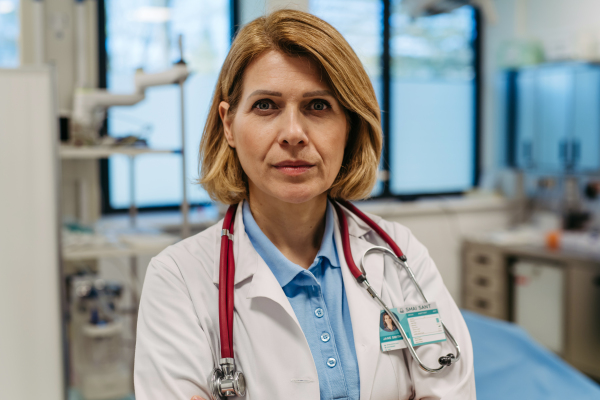 Portrait of female doctor standing in examination room. Medical setting.