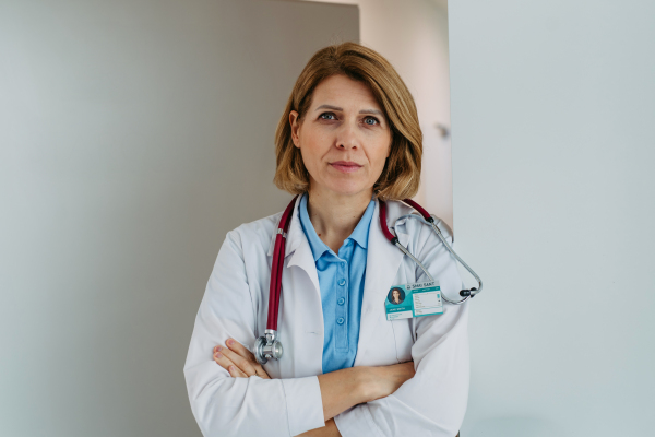 Portrait of female doctor standing in examination room. Medical setting.