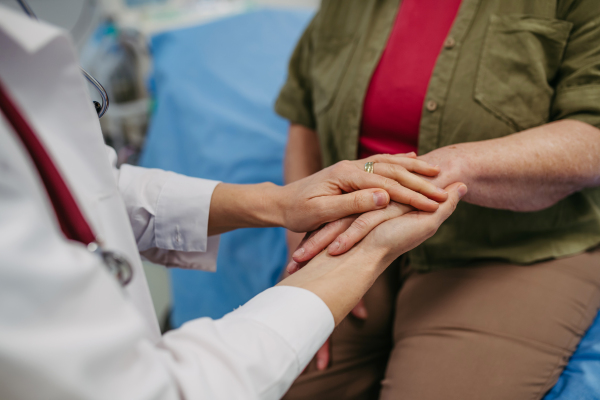 Caring doctor holding senior patient hand, compassionate gesture.