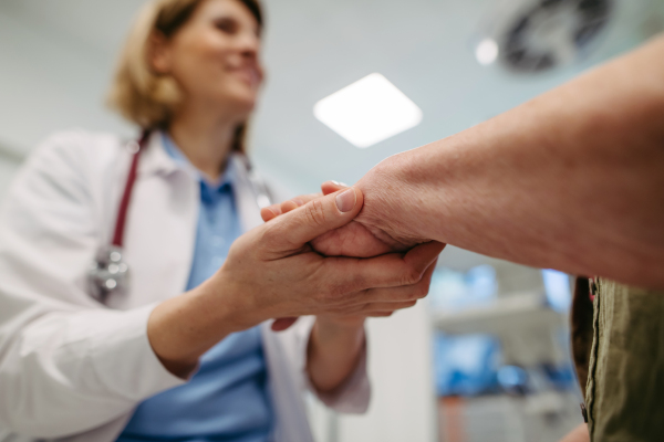 Caring doctor holding senior patient hand, compassionate gesture.