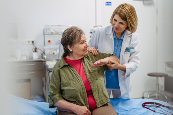 Geriatrician examining senior woman's mobility during routine check-up. Elderly care.