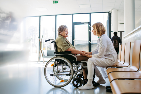 Elderly patient in wheelchair talking with female physician. Senior health care.