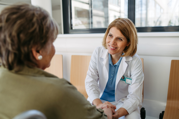 Elderly patient in wheelchair talking with female physician. Senior health care.
