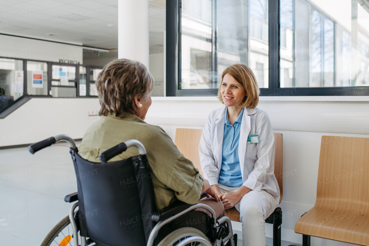 Elderly patient in wheelchair talking with female physician. Senior health care.