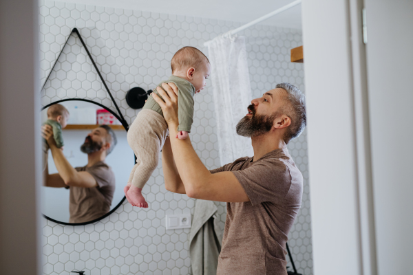 Portrait of father holding baby son in his arms.