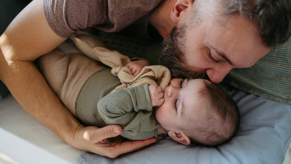 Father putting the baby to sleep, kissing him on head and soothing him.