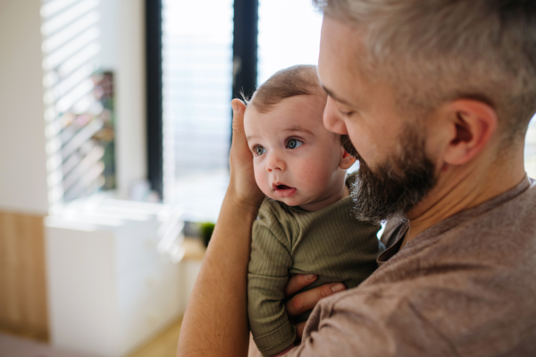 Portrait of father holding baby son in his arms.