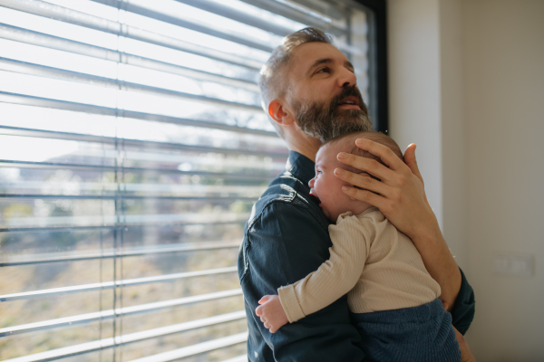 Father comforting his crying baby son, holding him in arms.