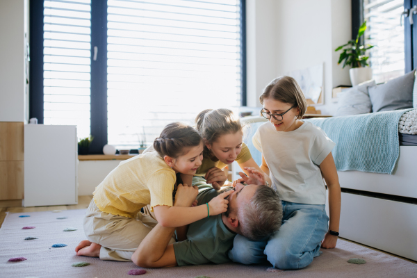 Portrait of father with three daughters at home. Girl dad concept.