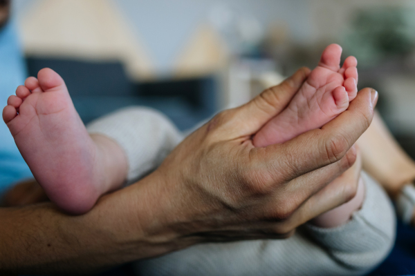 Dad holding little baby boy's feet. Fathers day.