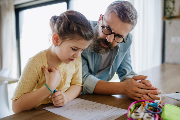 Father helping his daughter with their homework.