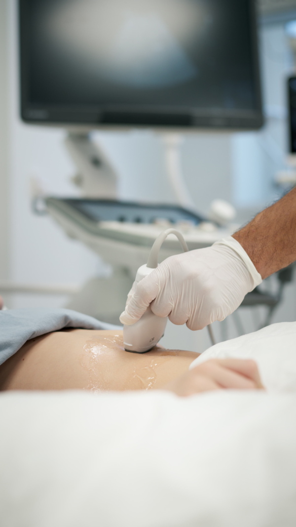 Close up of doctor using ultrasound probe to check on young boy, abdominal ultrasound.