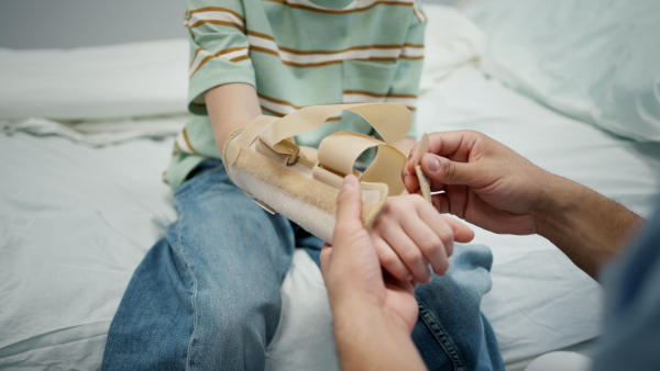 Close up of young pediatric patient receiving orthopedic wrist brace after arm injury.