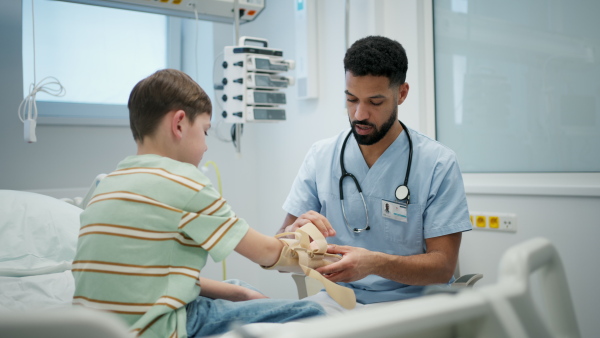Young pediatric patient receiving orthopedic wrist brace after arm injury.