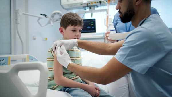 Male doctor giving vaccine to young boy during childhood immunization.