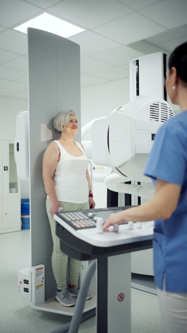 Senior woman positioned on radiographic wall stand for diagnostic imaging