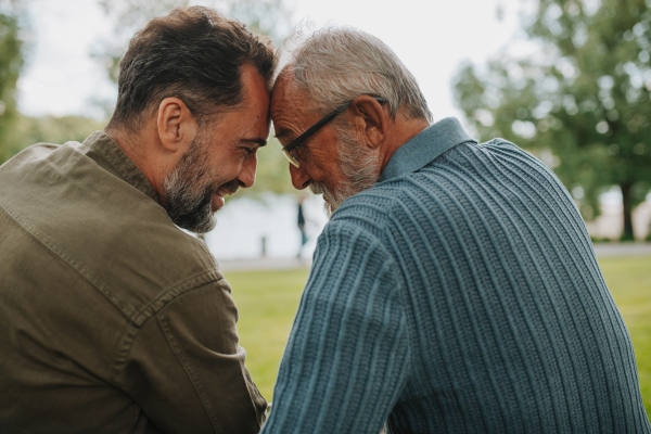 Father and adult son sharing a peaceful moment, touching with foreheads. Fathers day concept.