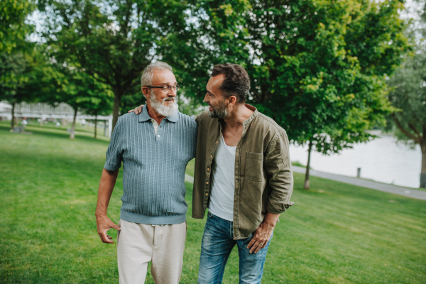 Senior dad and middle-aged son enjoying peaceful walk in park. Fathers day concept.