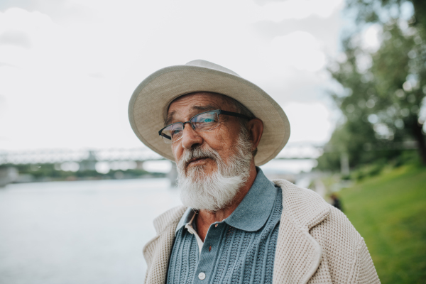 Pensive senior man looking at river. Peaceful moment.