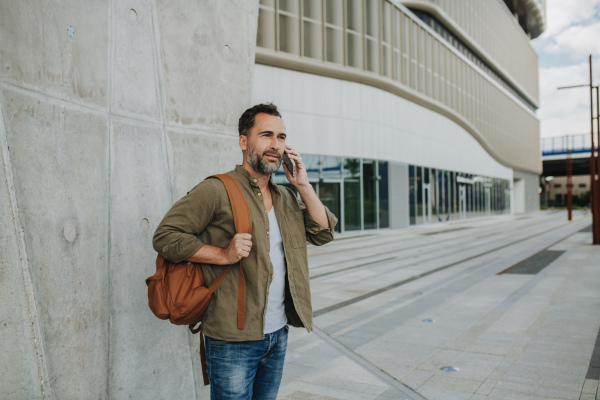 Portrait of confident middle-aged man making phone call outdoors.