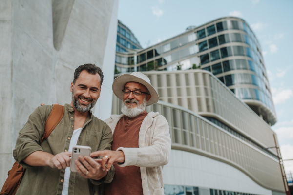 Mature son and father traveling together, looking at map on smartphone.