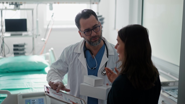 Pharmaceutical sales respresentative with doctor, hospital setting.