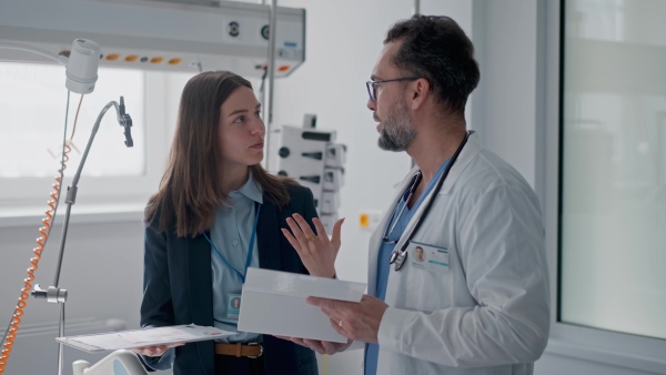 Pharmaceutical sales respresentative with doctor, hospital setting.