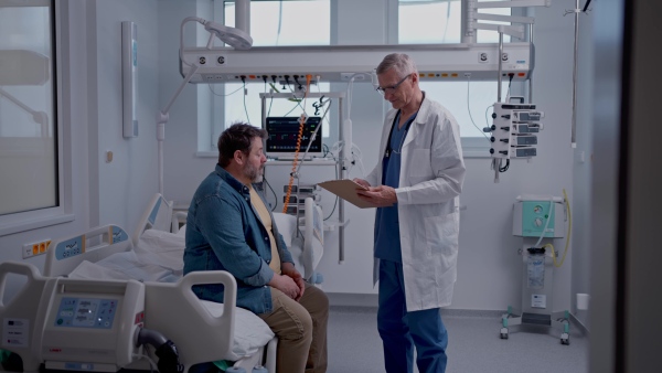 A doctor explaining the risks of leaving the hospital early as the patient prepares to sign an AMA form.