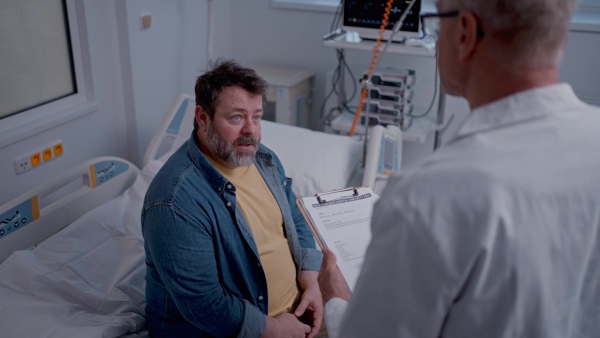 A doctor explaining the risks of leaving the hospital early as the patient prepares to sign an AMA form.