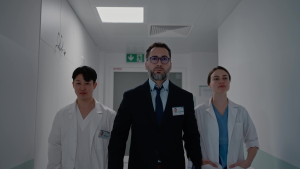 A manager with doctors walking thourgh hospital corridor.