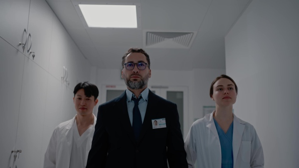 A manager with doctors walking thourgh hospital corridor.